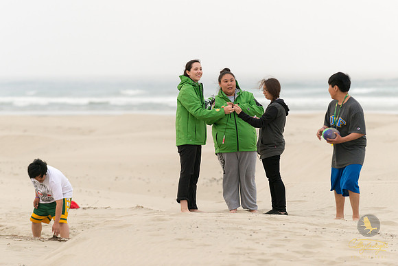 Program Coordinator, Anne Rittgers (center), hands out glow sticks to students during some much-deserved downtime at the beach.