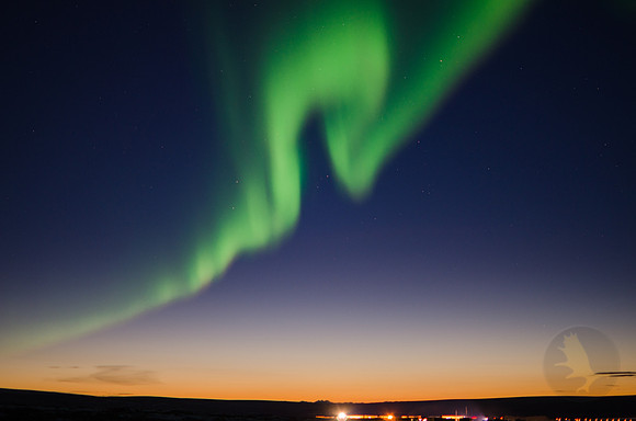 A thin ribbon of green aurora swirls over the northern sky of Alaska.