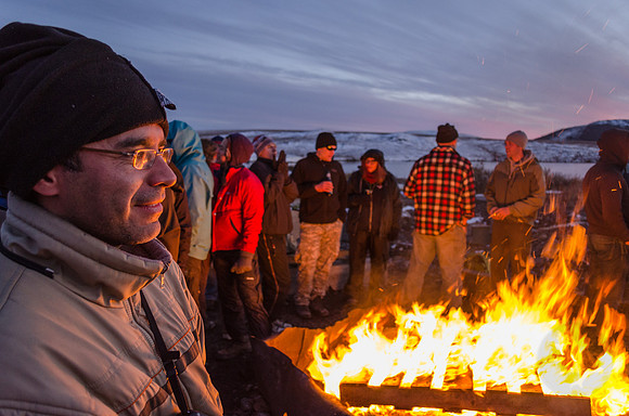 Geophysics graduate student Celso Alvizuri keeps warm next to a pallet fire at the Toolik Research Station on the North Slope of Alaska.