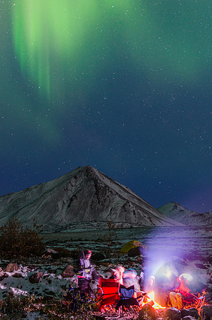 Late-night musings keep students awake around a warm campfire under the stars and the northern lights.
